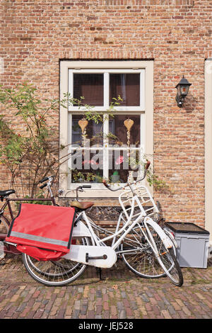 White classic noleggio parcheggiato contro un muro di mattoni di una antica casa in Heusden, provincia del Brabante, Paesi Bassi. Foto Stock