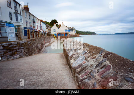 Persone bere su una torbida estati sera fuori la Devonport Inn presso il popolare villaggio sul mare di Kingsand Cornovaglia con scalo in primo piano e il mare offuscata dalla lunga esposizione Foto Stock