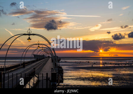Southport, Merseyside, 25 giugno 2017. Regno Unito Meteo. Un tramonto mozzafiato si appoggia sul molo a Southport nel Merseyside. Aperto per la prima volta nel 1860, si estende per una lunghezza di 1.108 metri (3,635 piedi) ed è il secondo più lungo in Gran Bretagna. Esso è stato elencato in grado II il 18 agosto 1975. La tramvia eseguito dalla passeggiata al Pier Head a varie volte nel molo di storia, e più recentemente da agosto 2005 fino a giugno 2015. Credito: Cernan Elias/Alamy Live News Foto Stock