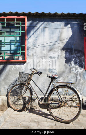 Vecchia bicicletta arrugginita parcheggiata in un hutong di Pechino, Cina. Foto Stock