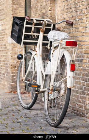 Bianco di trasporto bici con una cassa parcheggiate in un antico muro di mattoni, Amsterdam, Paesi Bassi. Foto Stock