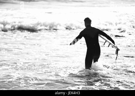 Silhouette di surfer in esecuzione in mare Foto Stock