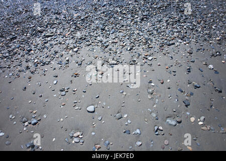 Un sacco di ciottoli sulla spiaggia sabbiosa Foto Stock