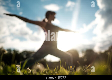 Montare sportivo donna caucasica facendo asana Virabhadrasana 2 Warrior pongono postura in natura. Foto Stock