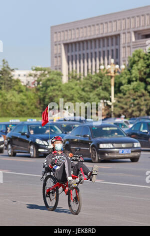 PECHINO-29 MAGGIO 2013. Uomo sportivo con cappellino sulla moto reclinata. I residenti di Pechino prendono le precauzioni contro l'inquinamento atmosferico in corso. Foto Stock