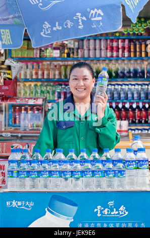 KUNMING-1 LUGLIO 2014. Ragazza in una stalla con bevande analcoliche e acqua. La qualità dell'acqua è una delle principali preoccupazioni della Cina a causa dell'inquinamento. Foto Stock