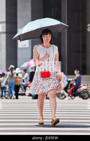 KUNMING-5 LUGLIO 2014. Ragazza cinese con un ombrello come blocco del sole. Fin dai tempi antichi una pelle pallida è un ideale assoluto di bellezza cinese. Foto Stock