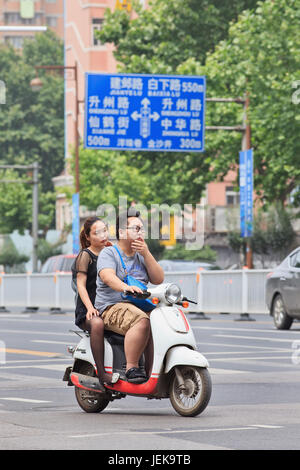 NANJING, 25 MAGGIO 2014. Uomo cinese sovrappeso con donna in bicicletta elettrica. Il tasso di obesità cinese è salito alle stelle negli ultimi trent’anni. Foto Stock