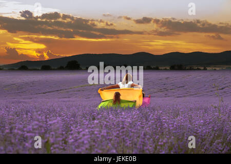 La madre e le sue due figlie a piedi attraverso un campo di lavanda azienda sciarpe, Bulgaria Foto Stock