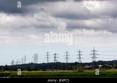 Alti tralicci di energia elettrica e la trasmissione di potenza cavi marciando attraverso la campagna con il fiume inferiore Prova, Totton, vicino a Southampton, Hants, Regno Unito Foto Stock