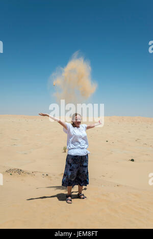 Donna che gioca con la sabbia sul Rub Al Khali desert, Dhofar Governatorato, Oman Foto Stock