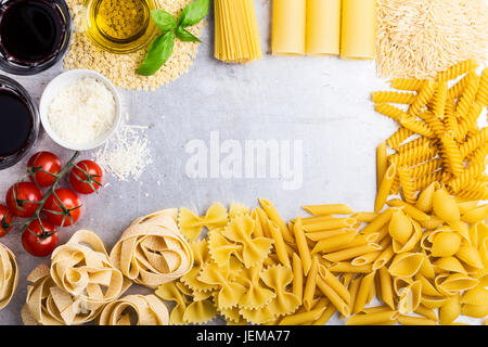 Cucina italiana di cottura Ingredienti e varietà di forme di pasta su sfondo grigio chiaro con copia spazio per testo, vista dall'alto Foto Stock