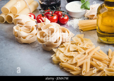 Varietà di pasta italiana forme. Gli ingredienti della cucina su sfondo grigio. Foto Stock