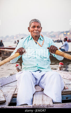 Un uomo indiano remare una barca per escursioni sul fiume Gange, Varanasi (India). Foto Stock