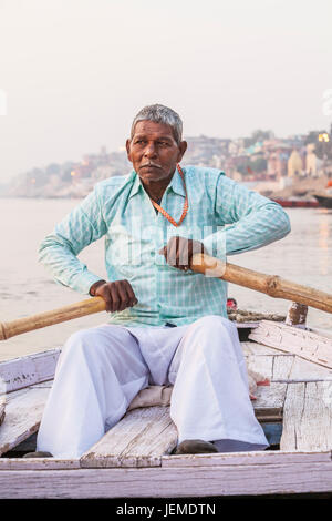 Un uomo indiano remare una barca per escursioni sul fiume Gange, Varanasi (India). Foto Stock