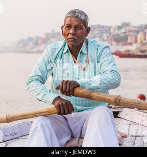 Un uomo indiano remare una barca per escursioni sul fiume Gange, Varanasi (India). Foto Stock