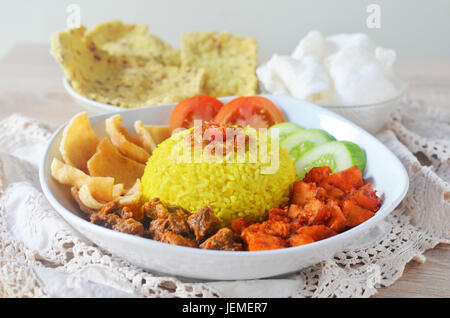 Indonesian profumato piatto di riso cotto con il latte di cocco e la curcuma,quindi il nome nasi kuning (riso giallo). Foto Stock