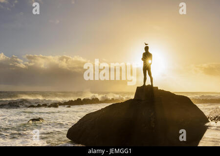 Silhouette di persona sulla roccia al tramonto Foto Stock