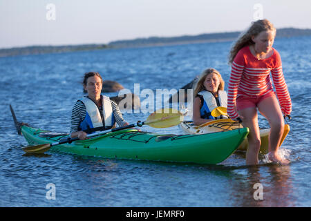 Ragazza tirando il kayak in mare Foto Stock