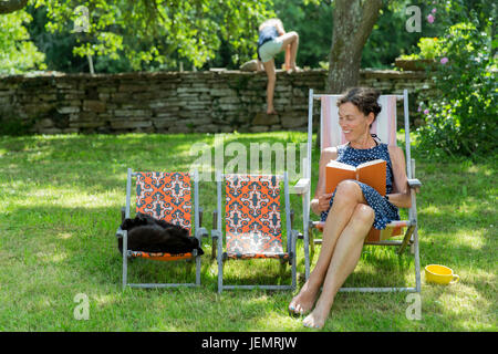 Donna libro di lettura sulla sedia sun Foto Stock