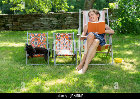 Donna sorridente sulla sedia sun Foto Stock