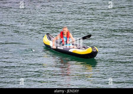 Una persona paddling in una canoa gonfiabile sul mare vicino al porto della popolare villaggio sul mare di Kingsand, Cornwall in estate Foto Stock