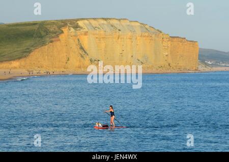 West Bay, Dorset, Regno Unito. Il 26 giugno, 2017. Regno Unito Meteo. Una donna su un paddleboard con il suo cane su un glorioso sunny serata presso la località balneare di West Bay nel Dorset. Photo credit: Graham Hunt/Alamy Live News Foto Stock