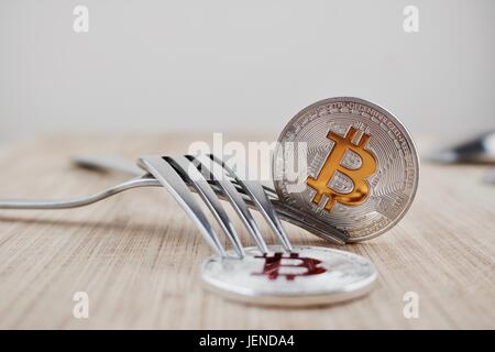 Valuta digitale argento fisico bitcoins sulla tavola di legno in cucina. Foto Stock