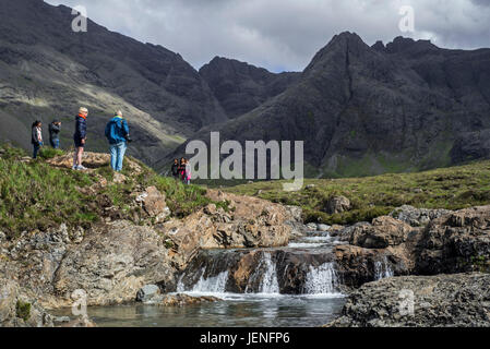 Black Cuillin e per i turisti che visitano la Fata Piscine, successione di cascate in Glen fragili sull'Isola di Skye, Highlands scozzesi, Scotland, Regno Unito Foto Stock