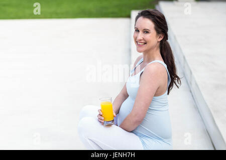 Donna incinta seduta sulle scale Foto Stock