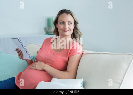 Donna incinta scrivere su blocco note Foto Stock