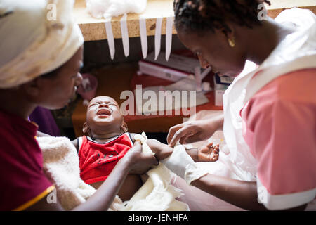 Un infermiere somministra il farmaco al bambino per via endovenosa in un ospedale di Bundibugyo, Uganda. Foto Stock