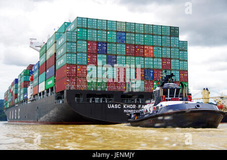 Contenitore enorme nave nel Canale di Panama con rimorchiatore Foto Stock