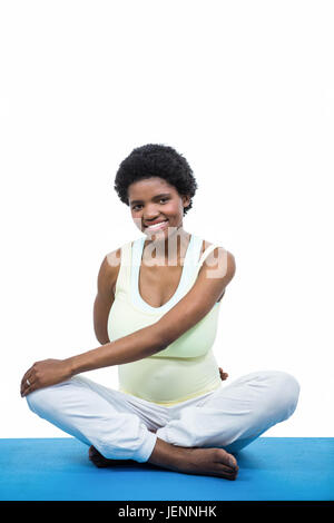 Donna incinta meditando sul tappetino Foto Stock