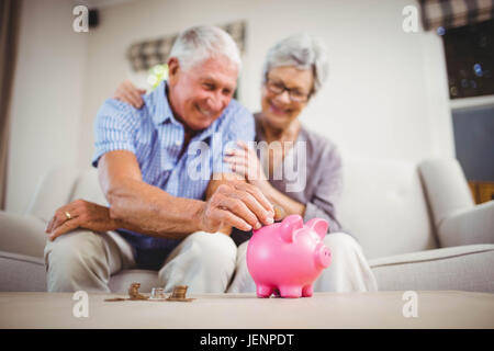 Senior uomo mettendo le monete nel salvadanaio Foto Stock