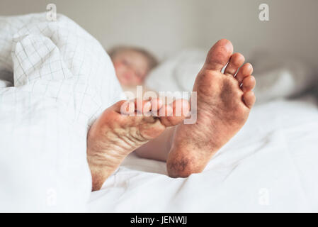 Childs piedi sporchi nel letto Foto Stock