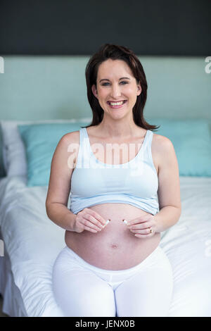 Donna incinta il taglio di una sigaretta in due Foto Stock