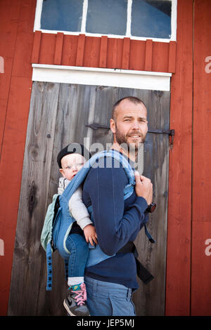 Padre che porta il suo Figlio bambino in baby carrier Foto Stock