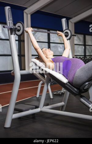 Sorridente donna incinta il sollevamento barbell Foto Stock