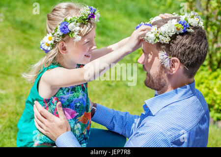 Padre con la figlia indossando ghirlande di fiori Foto Stock