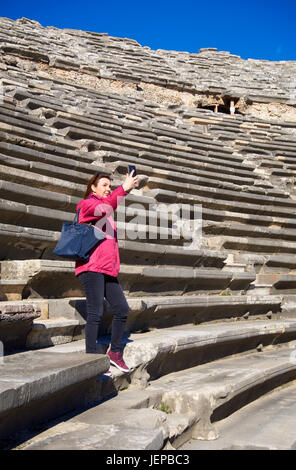 Tourist, alzarsi, facendo un selfie nell'antico teatro romano di lato. Costa Mediterranea, Antalya.La Turchia Foto Stock