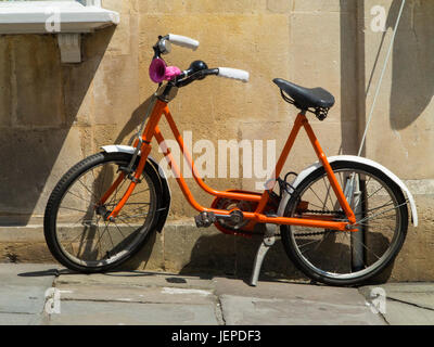 Un bambino arancione moto parcheggiata fuori un houe Foto Stock