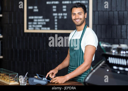 Piuttosto barista utilizzando un registratore di cassa Foto Stock