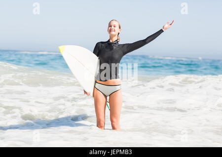 Donna con la tavola da surf in piedi in mare Foto Stock