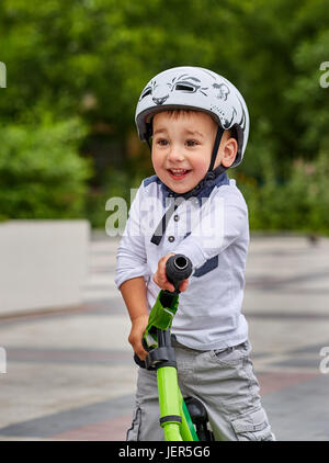 Bambino ragazzo in casco bianco in sella alla sua prima moto con un casco. In bici senza pedali. Foto Stock