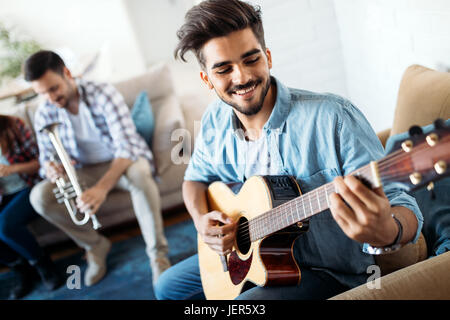 Giovane uomo bello suonare la chitarra per i suoi amici Foto Stock