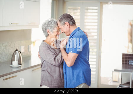 Felice coppia senior romancing in cucina Foto Stock