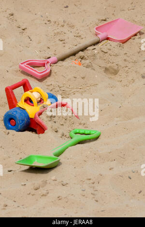 Giocattoli per bambini in una buca di sabbia area di gioco Foto Stock