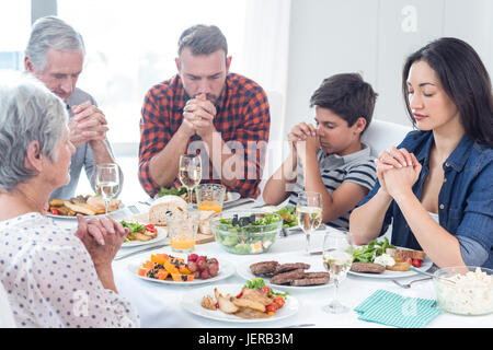 Famiglia di pregare insieme prima del pasto Foto Stock