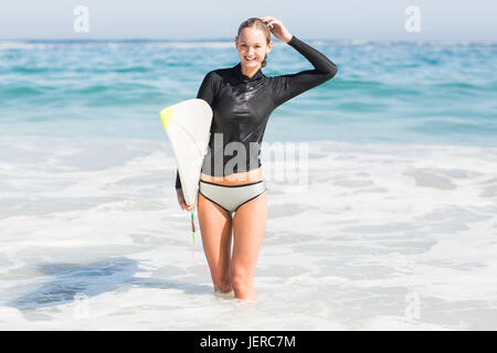 Donna felice con la tavola da surf in piedi in acqua Foto Stock